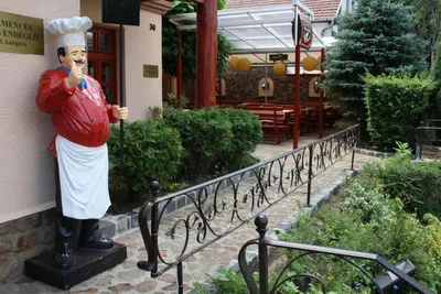 Szakácsszobor a vendéglő bejáratánál, kovácsoltvas korláttal